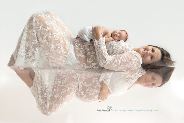 mother holding newborn lying of floor with reflection of same mother when she was pregnant