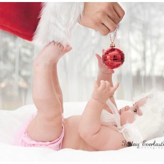 Cute baby catching Christmas ornament held by Santa