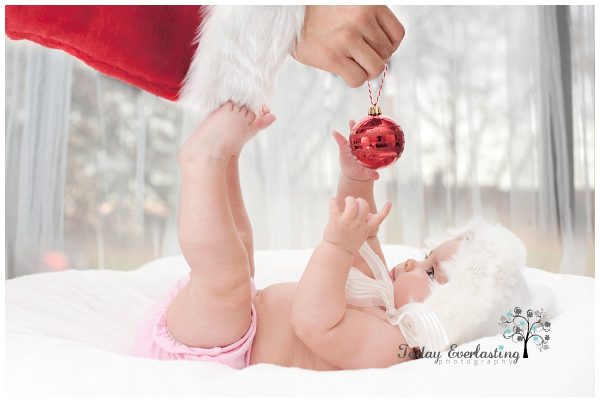 Cute baby catching Christmas ornament held by Santa