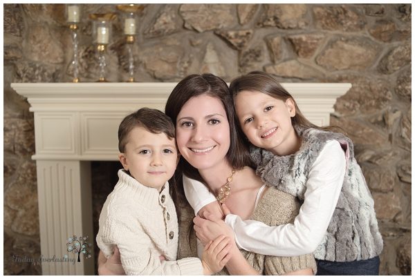A mother is snuggling with her two children.